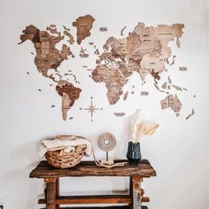 a wooden table topped with a vase filled with flowers and a world map on the wall