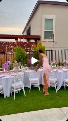 a woman standing in front of a table filled with white and pink tables cloths