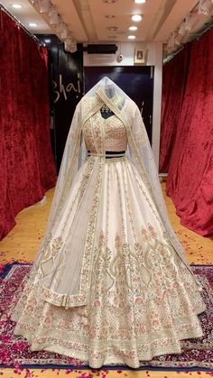 a wedding gown on display in front of red curtains