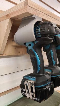 two cordless drillers sitting on top of each other in front of a wooden shelf