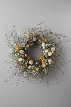 a wreath with yellow and white flowers hanging on the wall next to a gray wall