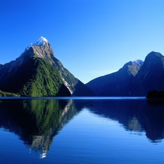 the mountains are reflected in the still water