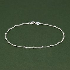 Genuine 925 Sterling Silver Ball Beaded Curb Chain Anklet 92.5% Pure Sterling Silver - thin, fine, & delicate 1mm diamond-cut curb chain anklet with beads at every 1cm, bolt ring fastening, 21.59cm (8.5 inches) long. All of our items are crafted in the highest quality Solid Sterling Silver and finished to perfection. Realtime Design Ltd is Assay Assured. All retailers that display the Assay Assured Trustmark, are part of a scheme that guarantees their customers that all of the precious metal (not exempt by weight) sold by them in an item, carries the legally required independent hallmark. This hallmark verifies the precious metal content. To have your piece hallmarked, there is an additional fee which you can message us about. Satellite Bracelet, 2mm Beads, Bolt Ring, Dainty Bracelet, Silver Chain Bracelet, Dainty Bracelets, Chain Anklet, Anklet Jewelry, Body Jewellery