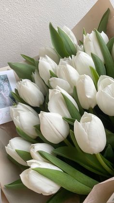 a bouquet of white tulips in a box with a photo on the side