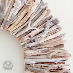 a wreath made out of driftwood is displayed on the wall in front of a white wall