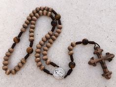 Custom Catholic Saint Benedict gemstone & wood rosary beads, wooden and tigers eye, walnut cross and custom rosary center | AndavyGifts ---------------------------------------- This rosary made by my husband Joe is one of a kind, but can still be customized. MATERIALS The cross is carved out from a single piece of untreated walnut wood. The beads are plain smoky brown dyed wood beads and larger, matte polished tiger's eye gemstone beads. The beads are strung and knotted with durable dark bro