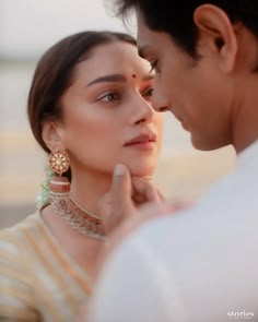 a man standing next to a woman wearing earrings