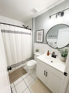 a bathroom with a white toilet sitting next to a sink and a mirror above it