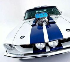 a blue and white mustang muscle car with the hood up on it's headlight