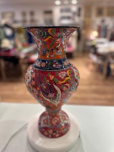 a colorful vase sitting on top of a white table