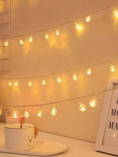 a coffee cup on a saucer next to a lite - up string of lights