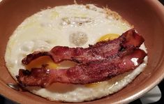 an egg and bacon breakfast is in a brown bowl on the stove top, ready to be eaten