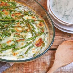 a casserole dish with green beans and cheese in it on a wooden table