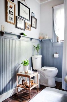 a white toilet sitting in a bathroom next to a plant on top of a wooden table