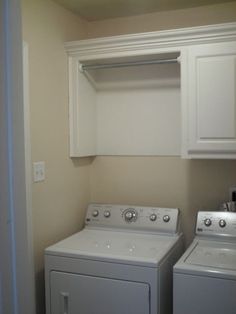 a washer and dryer in a small room with white cabinetry on the wall