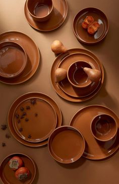 the table is set with brown dishes and cups