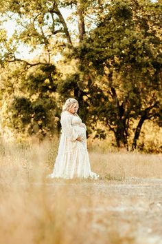 a pregnant woman standing in the middle of a field