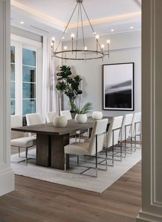 a dining room table with white chairs and a chandelier