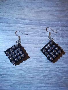 a pair of black and silver earrings on top of a wooden table