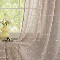 a vase filled with flowers sitting on top of a window sill next to a curtain