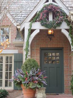 the front entrance to a home decorated for christmas with wreaths and potted plants