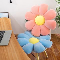 a laptop computer sitting on top of a wooden desk next to a flower shaped chair