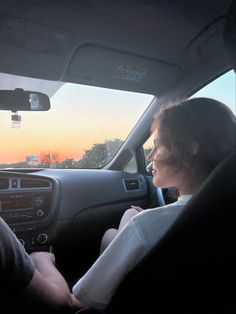 two people sitting in the driver's seat of a car at sunset or dawn