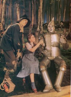 an old photo of two people standing next to a robot