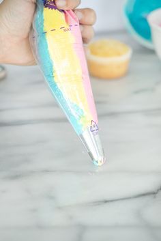 a person is holding an umbrella shaped like a rainbow colored umbrella with a pink, yellow and blue handle