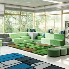 a living room with green couches and blue rugs in front of large windows