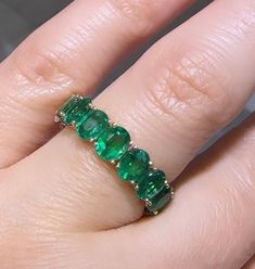 a close up of a person's hand with an emerald ring on their finger