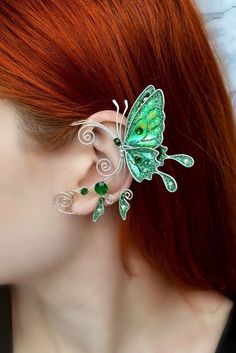 a woman with red hair wearing a green butterfly ear cuff