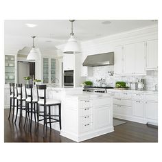 a large kitchen with white cabinets and wooden floors