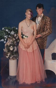 an old photo of two people dressed up in formal wear and standing next to each other