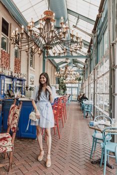 a woman is standing in the middle of a room with chairs and chandeliers