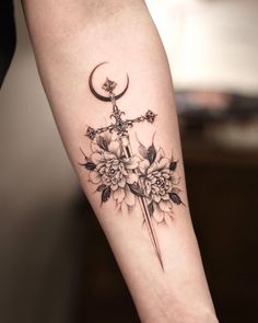 a cross with flowers and a crescent tattoo on the arm is shown in black ink