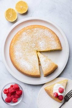 a white plate topped with a cake covered in powdered sugar and raspberries