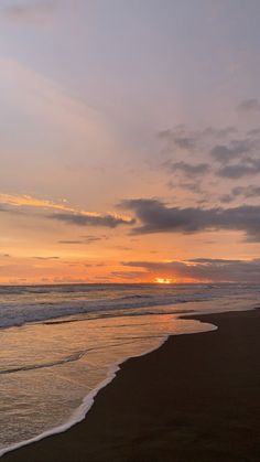 the sun is setting over the ocean with waves coming in