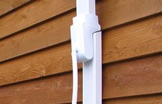 an electronic device mounted to the side of a wooden wall next to a house with siding on it