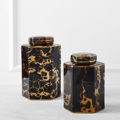 two black and gold canisters sitting next to each other on a white floor