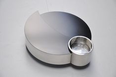 a stainless steel object on a white surface with a silver cup in the middle,