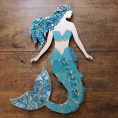 a paper cut out of the shape of a mermaid sitting on top of a wooden table