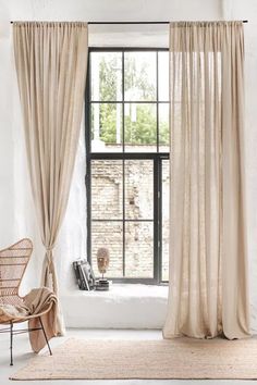 a chair sitting in front of a window next to a white rug and a black framed window