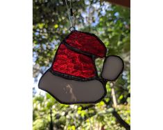 a stained glass christmas ornament hanging from a tree in front of some trees