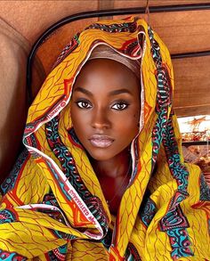 an african woman wearing a yellow and blue hoodie with intricate designs on her face