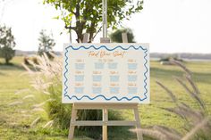 an easel with a wedding seating chart on it in the middle of a field