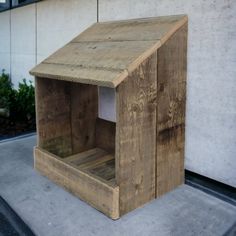 a dog house made out of pallet wood on the side of a building in front of a planter