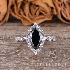 a black and white diamond ring on top of a wooden table with roses in the background