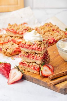 strawberry crumbler bars stacked on top of each other next to a bowl of whipped cream