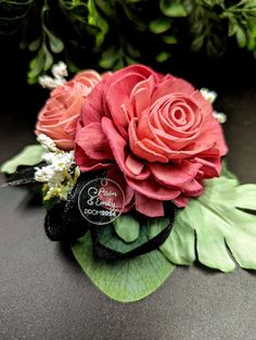 a bouquet of flowers with green leaves and red roses on the top, sitting on a table